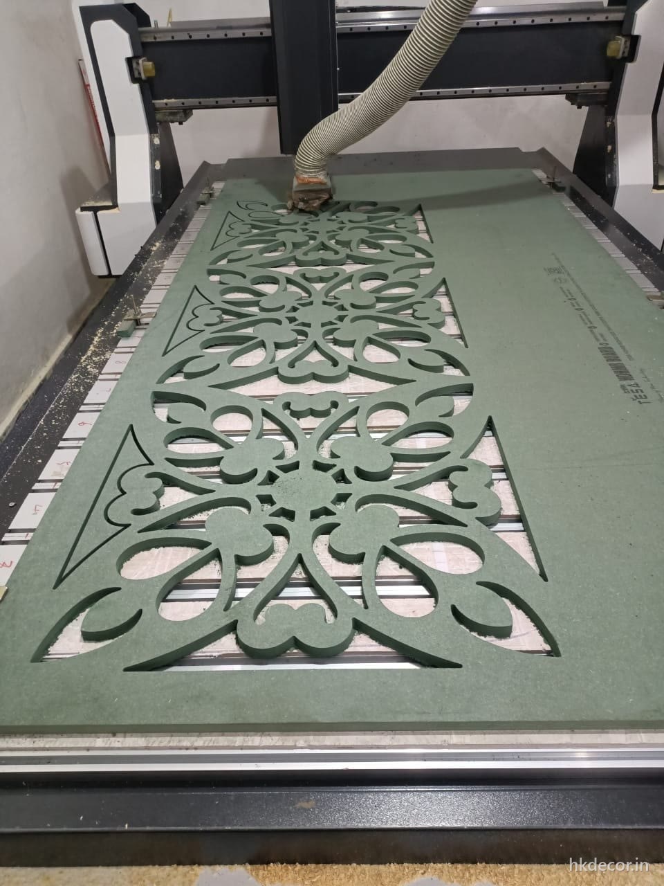 CNC router cutting a floral jaali pattern through a board on the bed at Dream3 Bijwasan